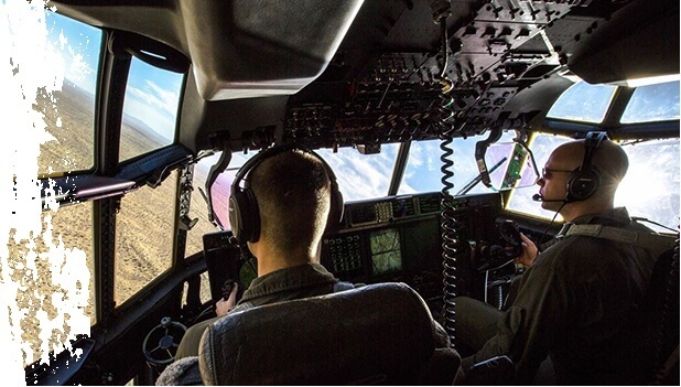 Interior Image of Two Military Men Flying A Helicopter Over A Desert